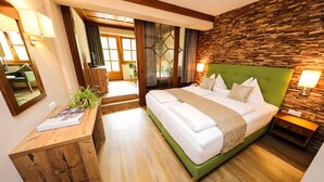 Une chambre moderne avec une tête de lit rembourrée de tissu vert, un plancher en bois, une table de chevet en bois, une table de nuit avec une lampe et une grande fenêtre avec des rideaux.