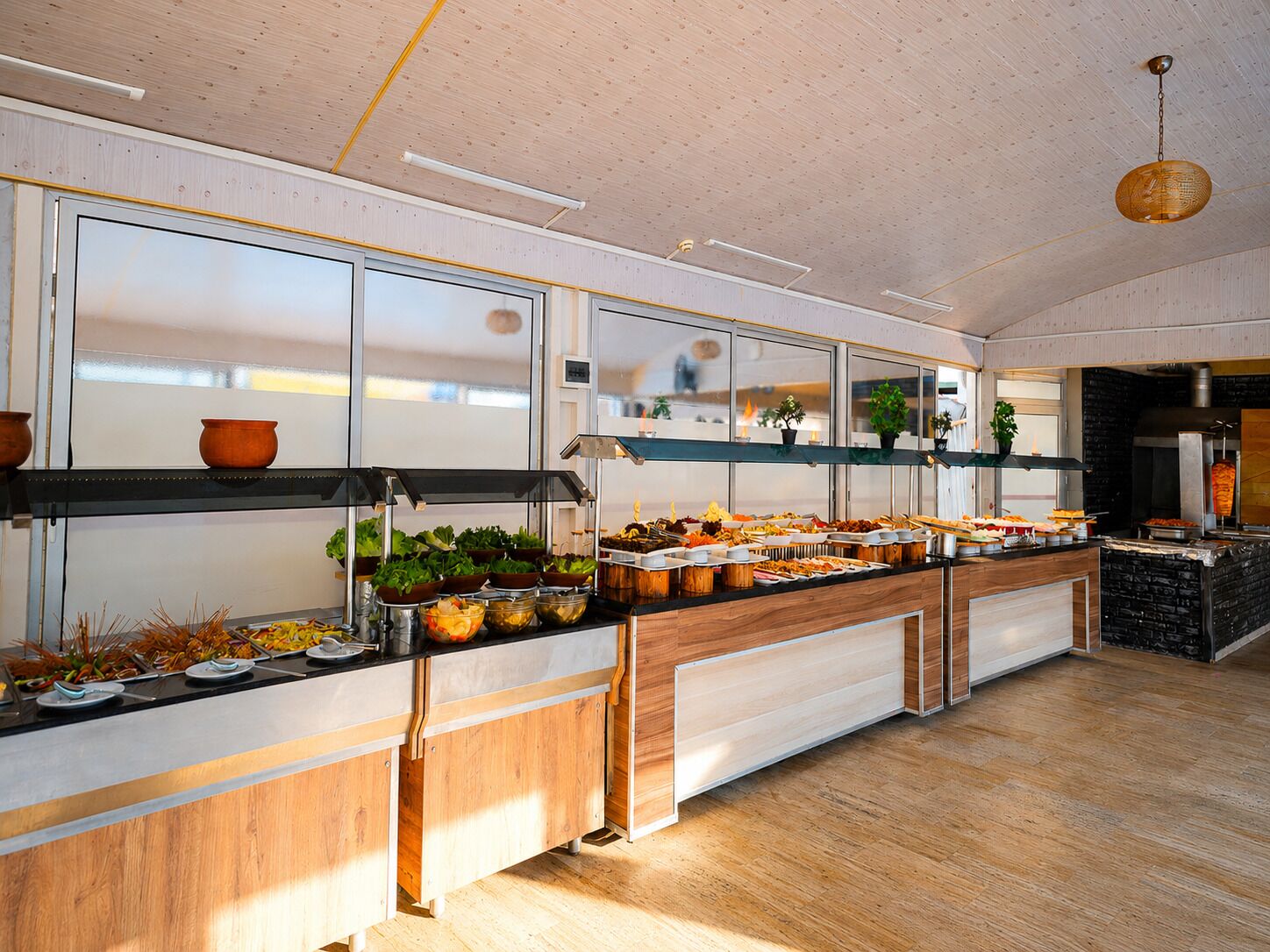 A modern kitchen with wooden cabinets, a black countertop, and a hanging light fixture.