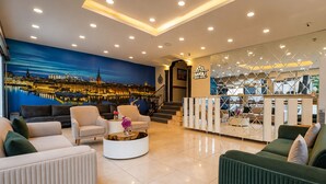 Um saguão de hotel com um mural da paisagem urbana, uma recepção e modernos arranjos de assentos.