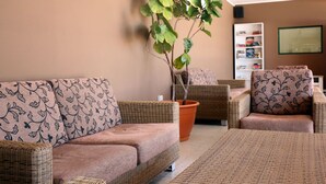 Un salon chaleureux avec des meubles en osier, une plante en pot et une bibliothèque.