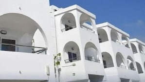 Un bâtiment blanc doté de nombreux balcons et de fenêtres en arc de cercle.