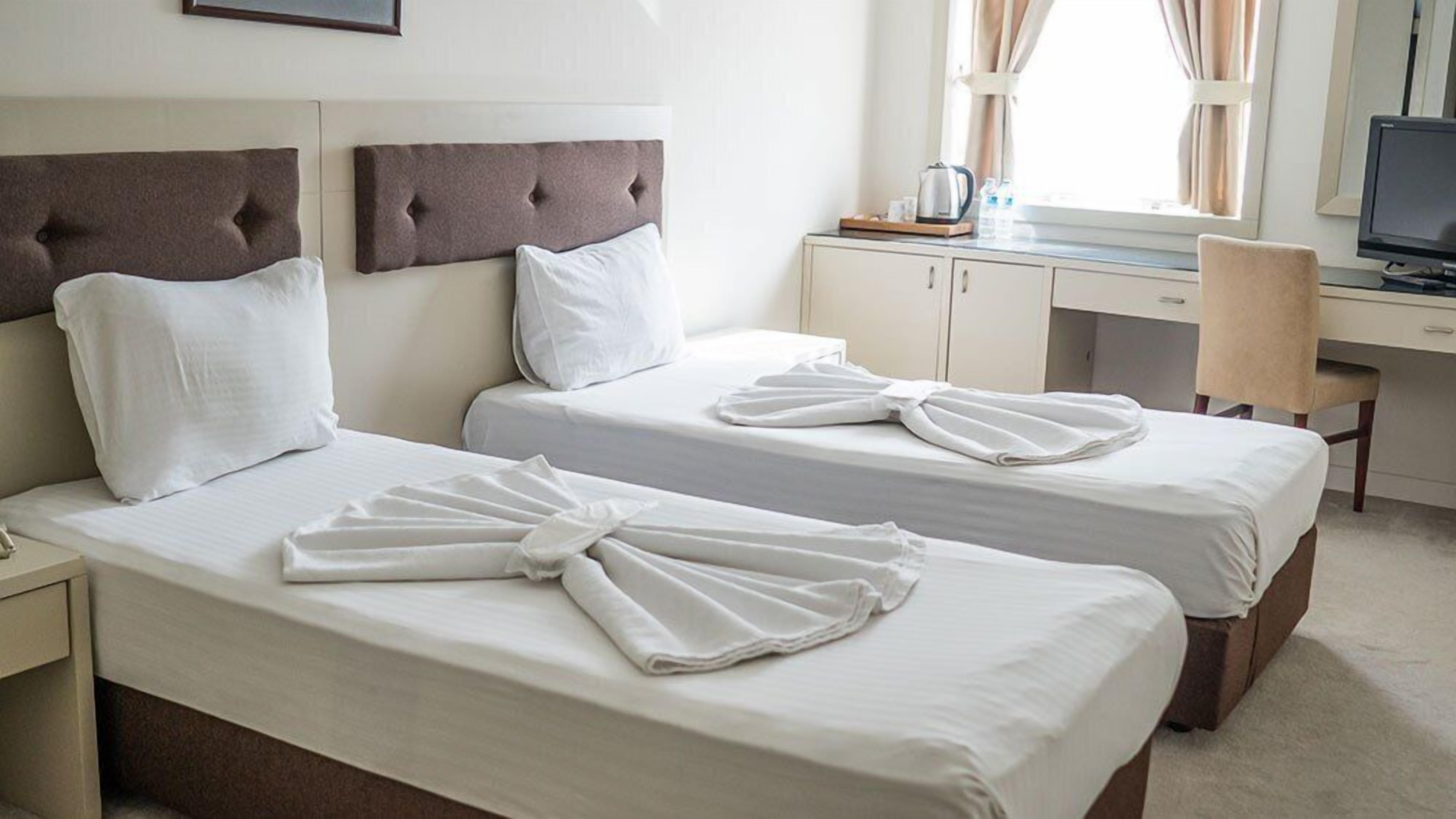 Hotellihuone, jossa on kaksi sänkyä, työpöytä, tuoli ja televisio.