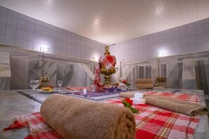 Une chambre d’hôtel avec un lit, une table recouverte d’une nappe à carreaux rouges et blancs, une statue dorée et des serviettes.