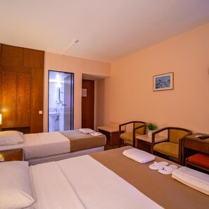 Une chambre d’hôtel avec deux lits, un bureau, une chaise et une petite table sur laquelle est posée une plante.
