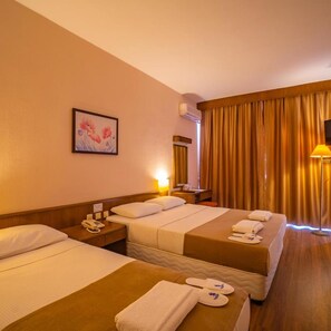 Une chambre d’hôtel avec deux lits, une table de chevet avec un téléphone, une lampe et un tableau au mur.