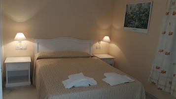 Cama bem arrumada com roupa de cama listrada e duas luminárias de cabeceira.