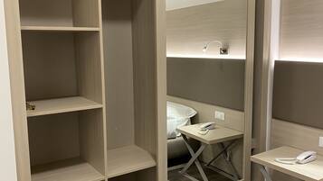 A walk-in closet with multiple shelves, a mirrored section, and a small desk with a telephone and a power strip.