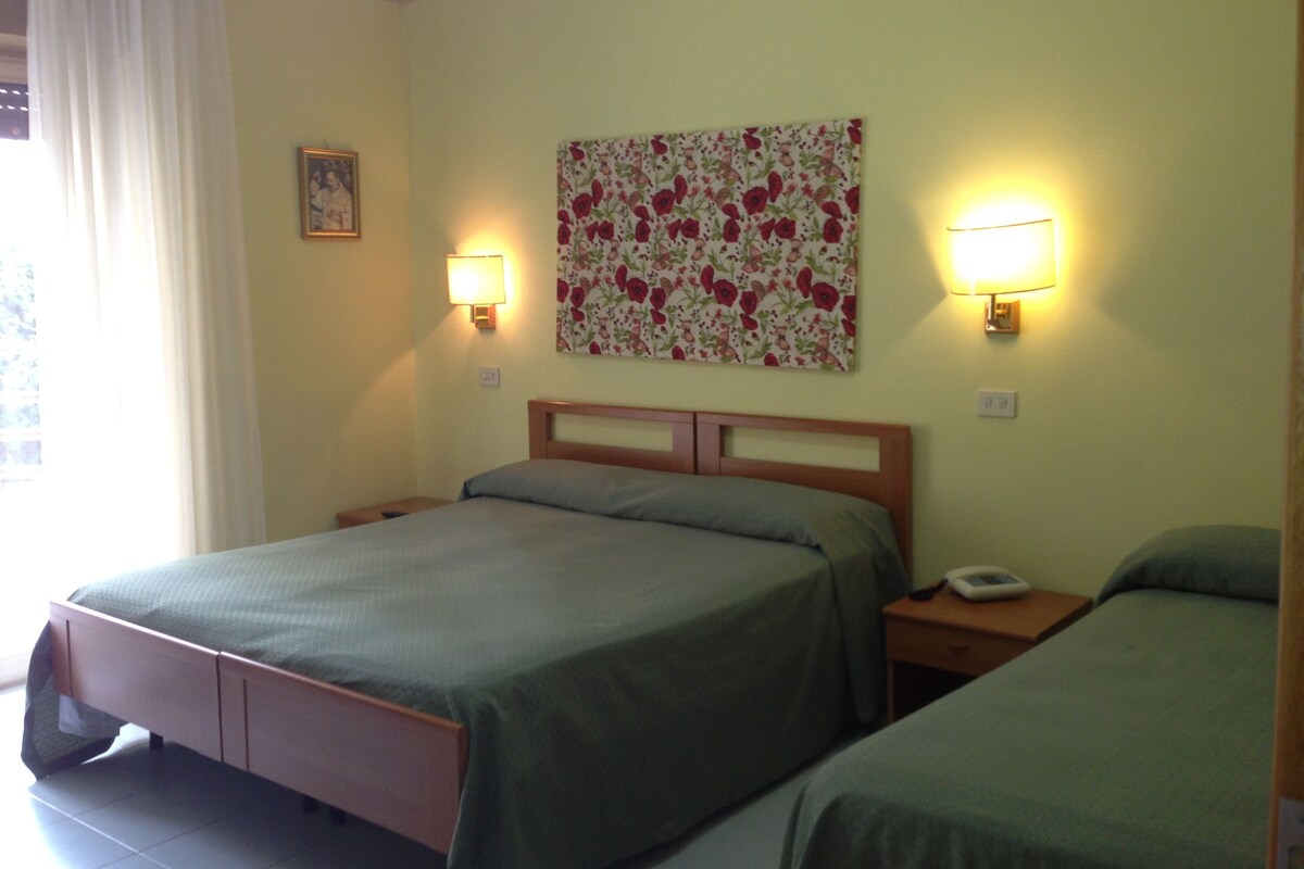 Une chambre d’hôtel avec deux lits, une décoration murale à motifs floraux et des lampes de chevet.