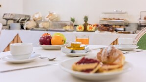 A breakfast setting with plates of food, a glass of orange juice, and a cup of coffee on a table. - Raeli Hotel Regio (Rome)