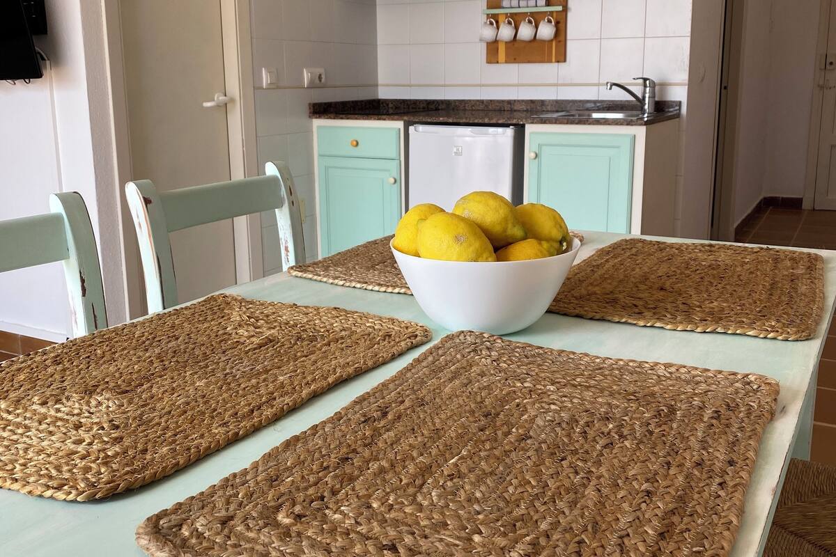 Eine Küche mit türkisfarbenen Schränken, einem weißen Kühlschrank und einer Zitronenschale auf der Arbeitsplatte.