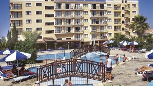 Zona de piscina de hotel con varias piscinas, sillas de descanso y sombrillas.