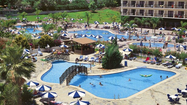 Un resort con varias piscinas, tumbonas y sombrillas.
