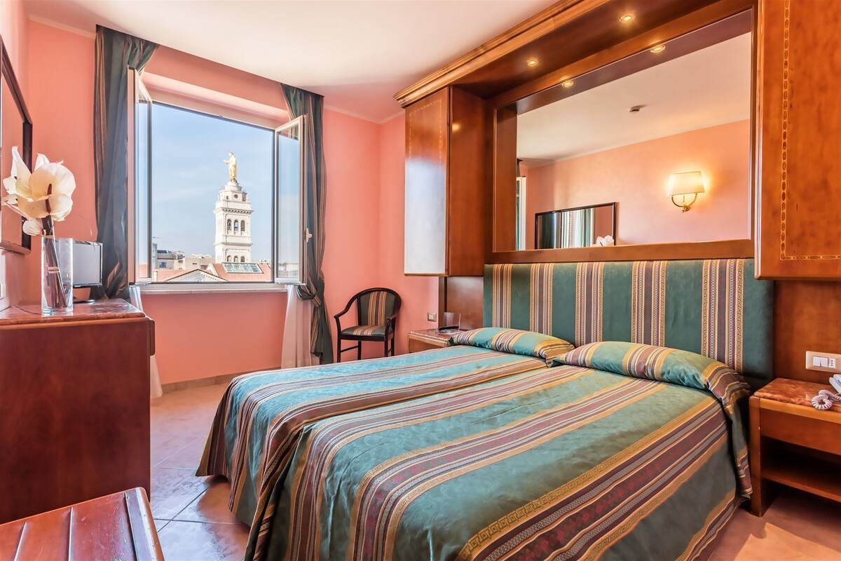 Une chambre d’hôtel avec un grand lit, un bureau, une chaise et une vue sur une tour.