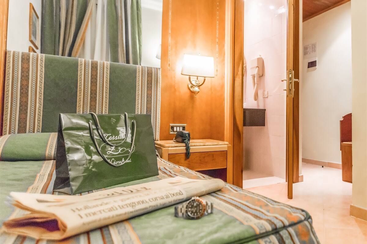 Une chambre d’hôtel avec un lit, une table de chevet, une lampe, un téléphone et une porte.