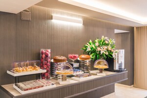 A buffet counter with various pastries, cakes, and a coffee machine.