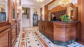 A grand lobby with a marble floor, wooden reception desk, and a large chandelier. - Raeli Hotel Siracusa (Rome)