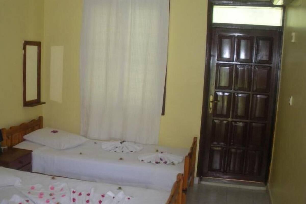 Una habitación con dos camas, una puerta de madera y un espejo en la pared.