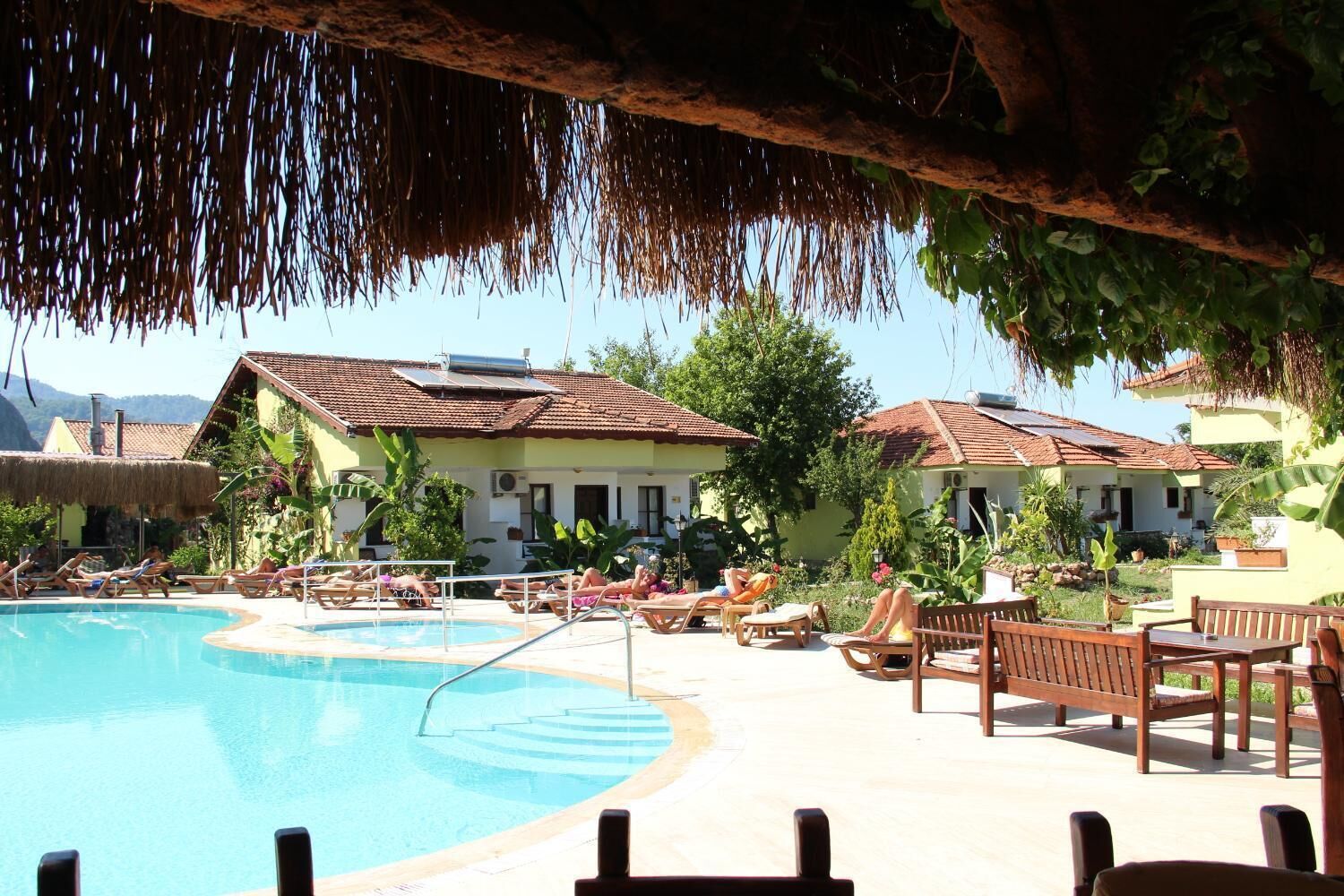 A pool area with lounge chairs and a building with a tiled roof.