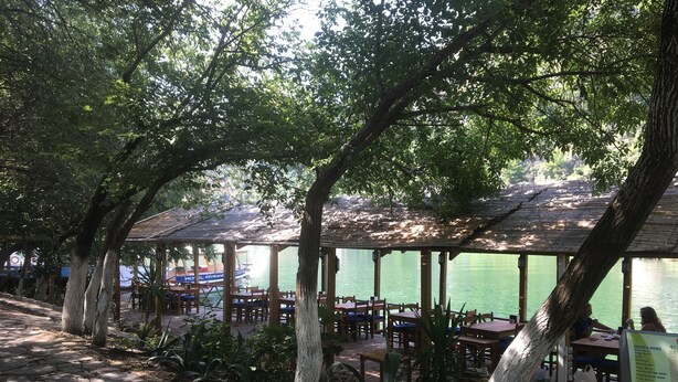 A riverside restaurant with outdoor seating, stone pathways, and a menu board. - Hotel Riverside (Ortaca)