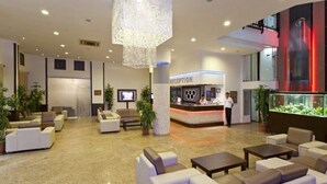 En rummelig lobby med moderne siddepladser, en receptionsdisk og et stort dekorativt lysarmatur.