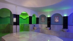 Spa-område med flere håndvaske, en stor marmorreception og grønne lyselementer.