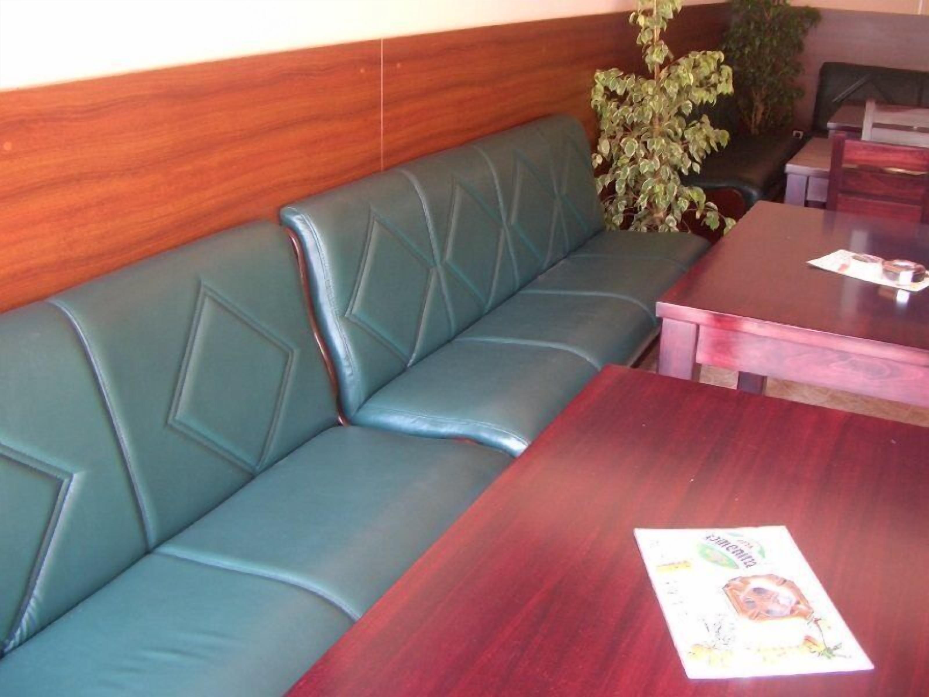 A green leather booth with a wooden wall and a table with a menu.