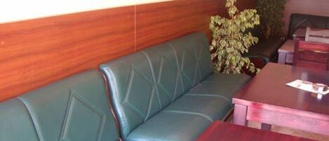 A green leather booth with a wooden wall and a table with a menu.