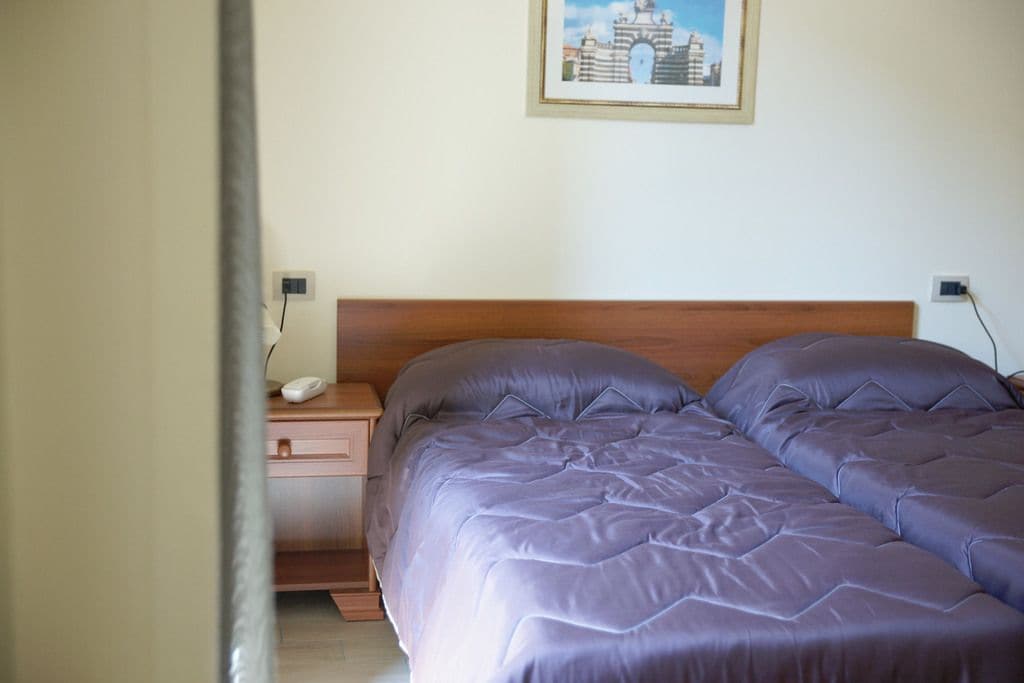 A bedroom with a wooden headboard, a bedside table with a phone, and a framed picture on the wall.