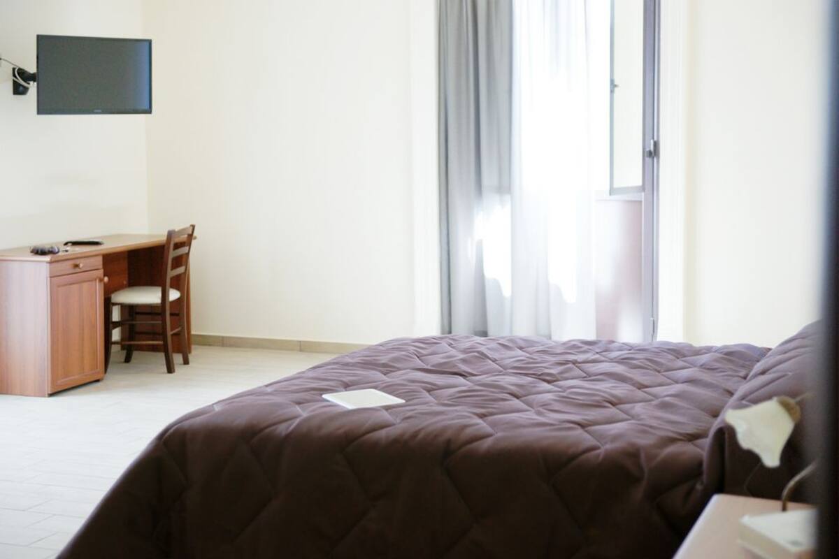 A bedroom with a bed, a desk, and a chair.
