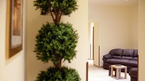A living room with a brown leather sofa, a small wooden table, and a potted plant. - Hotel Sofia (Catania)