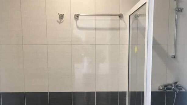 A bathroom with a toilet, a glass shower enclosure, and a towel rack. - Largo (Sunny Beach)