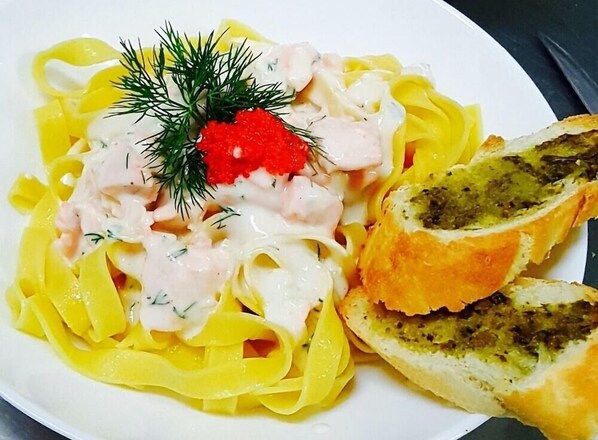 A plate of pasta with a creamy sauce, red caviar, and a sprig of dill. - Largo (Sunny Beach)