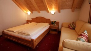 Una habitación con una cama de madera, una mesita de noche y un sofá.