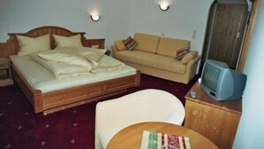 Un dormitorio con cama, sofá, televisión y una silla.