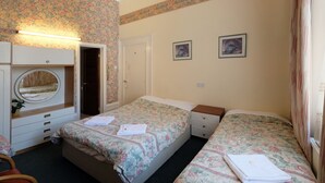 A bedroom with two beds, a dresser, a mirror, and a door. - Fairways Hotel Paddington (London)