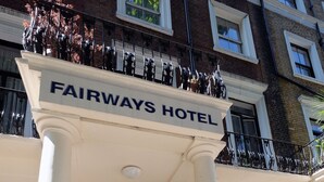 The entrance to the Fairways Hotel with a sign above the door, columns with numbers, and a small entrance area with steps. - Fairways Hotel Paddington (London)