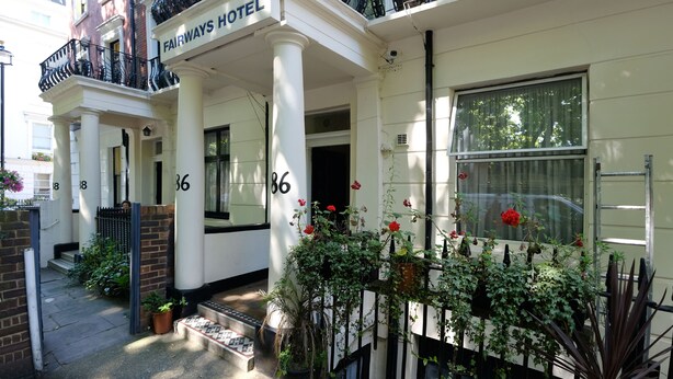 A building with a sign reading "Fairways Hotel," featuring a traditional facade with white columns, black railings, and numbered doors. - Fairways Hotel Paddington (London)