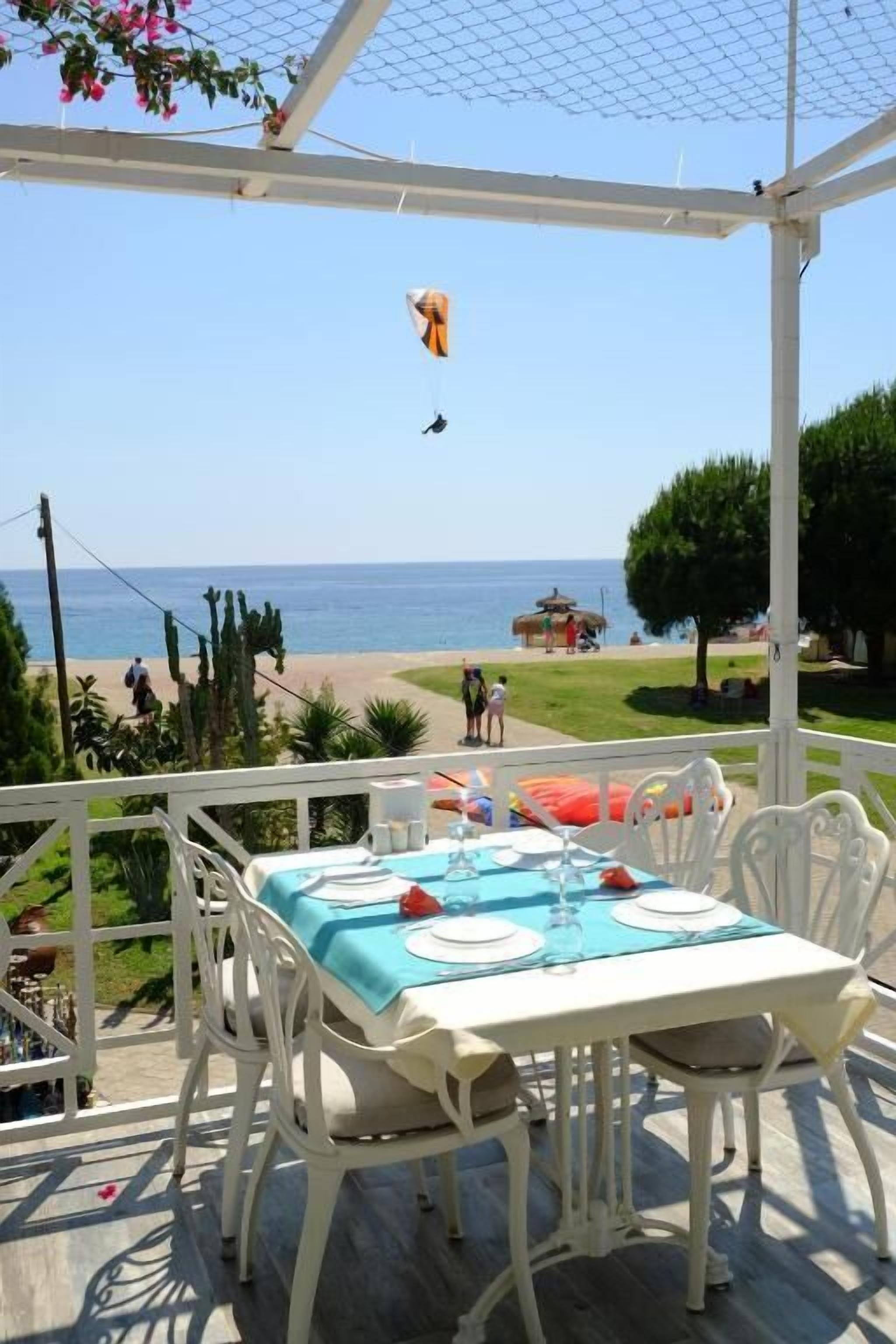 Un patio exterior con mesa lista para comer, con vistas a la playa.