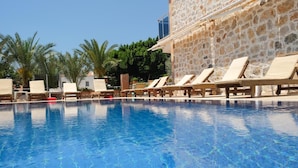 A swimming pool with lounge chairs and a stone building in the background. - The Kumsal Hotel Ölüdeniz (Fethiye)