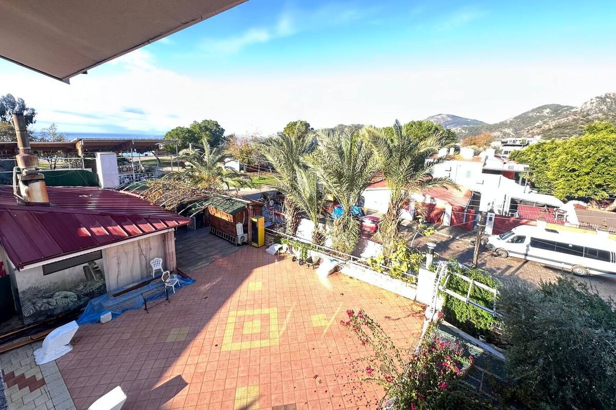 A courtyard with a tiled floor, palm trees, and a red-roofed building.