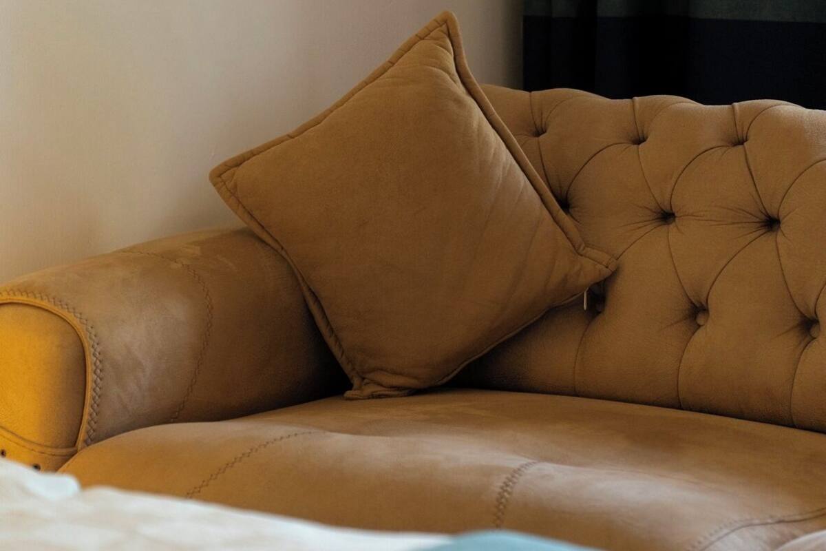 A bed with a tufted headboard and a single brown pillow.