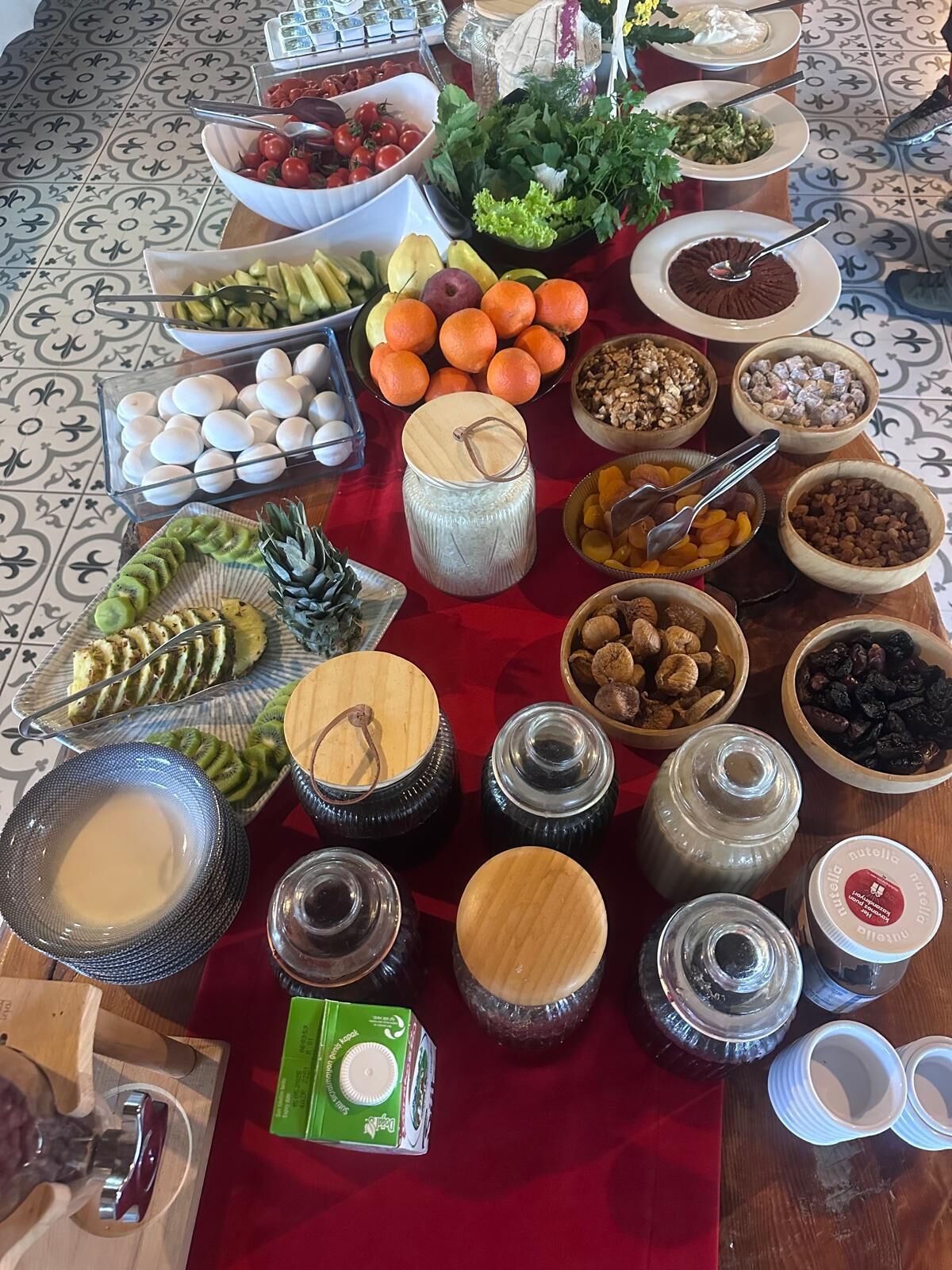 A table with various food items and condiments, including fruits, vegetables, and jars of spreads.