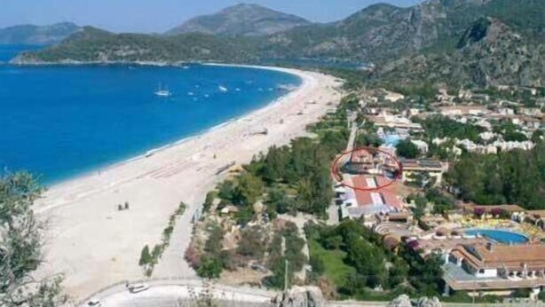 A coastal town with a beach, houses, and mountains. - The Kumsal Hotel Ölüdeniz (Fethiye)