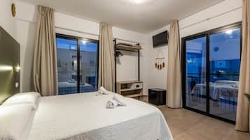 A hotel room with a bed, a desk, a TV, and a balcony with a view.