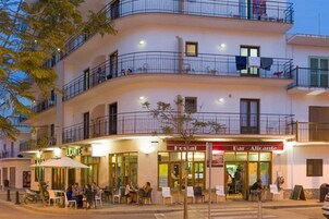 Un edificio de varios pisos con mesas al aire libre y un restaurante llamado 'Fosal'.