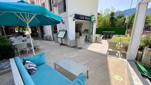 An outdoor seating area with a café bistro sign, wicker furniture, and a menu board. - Eda Hotel (Marmaris)