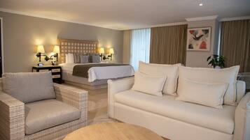 A hotel room with a bed, two bedside tables with lamps, a sofa, and a small round table.