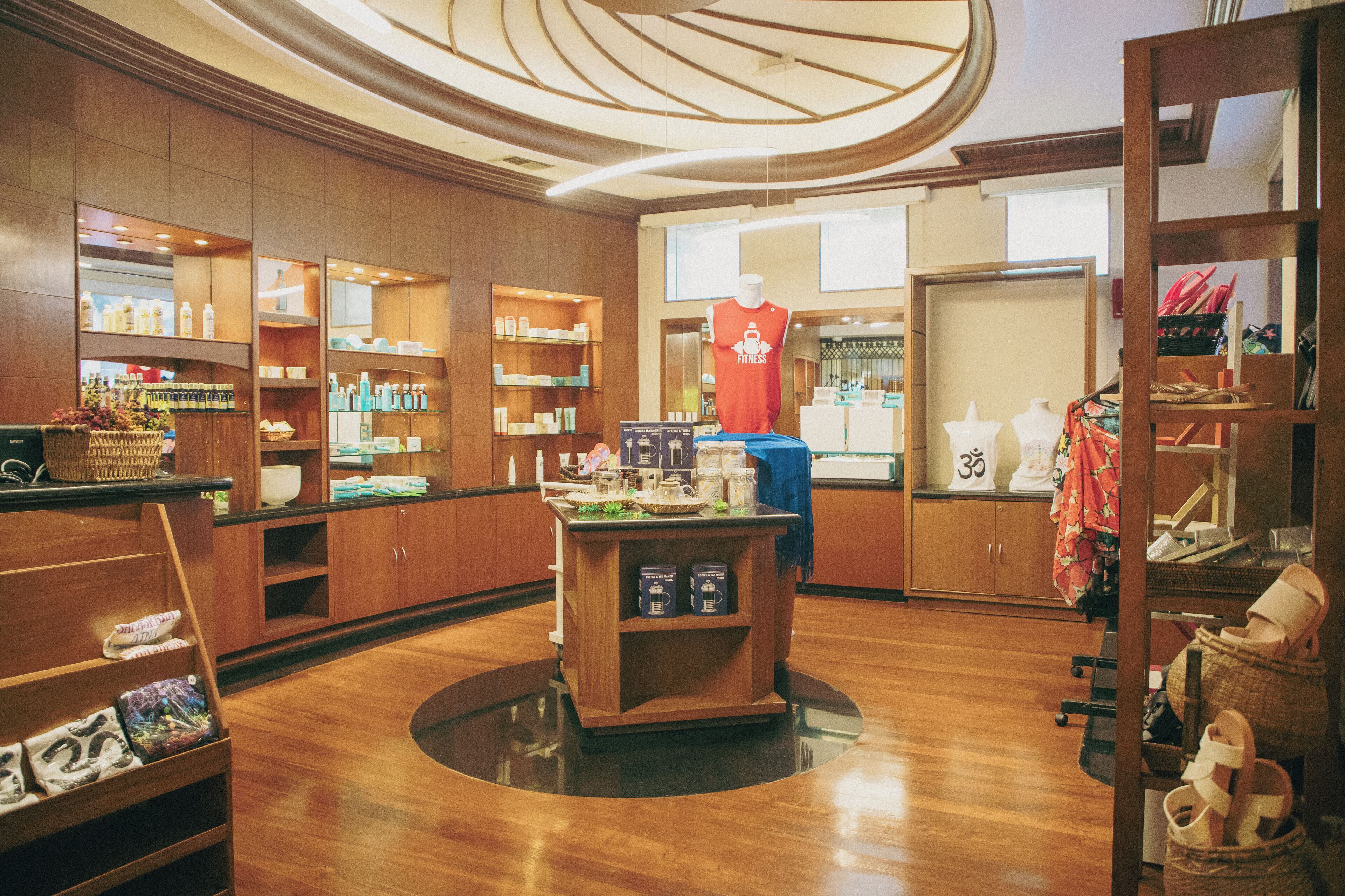A well-lit boutique hotel interior with wooden flooring, a central display table, and various shelves stocked with items.