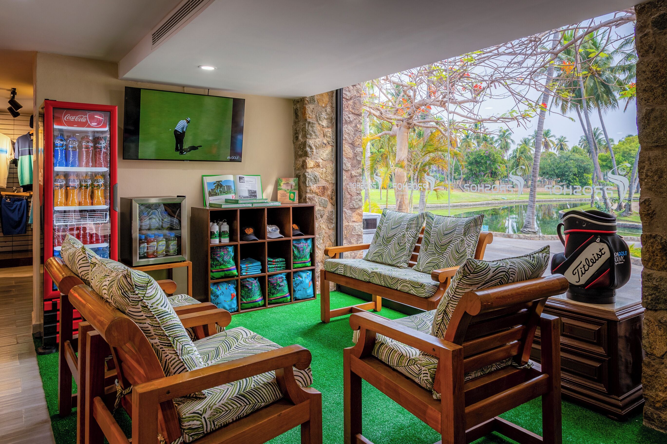 Una habitación con muebles de madera, televisión, refrigerador Coca-Cola y vista a un campo de golf.