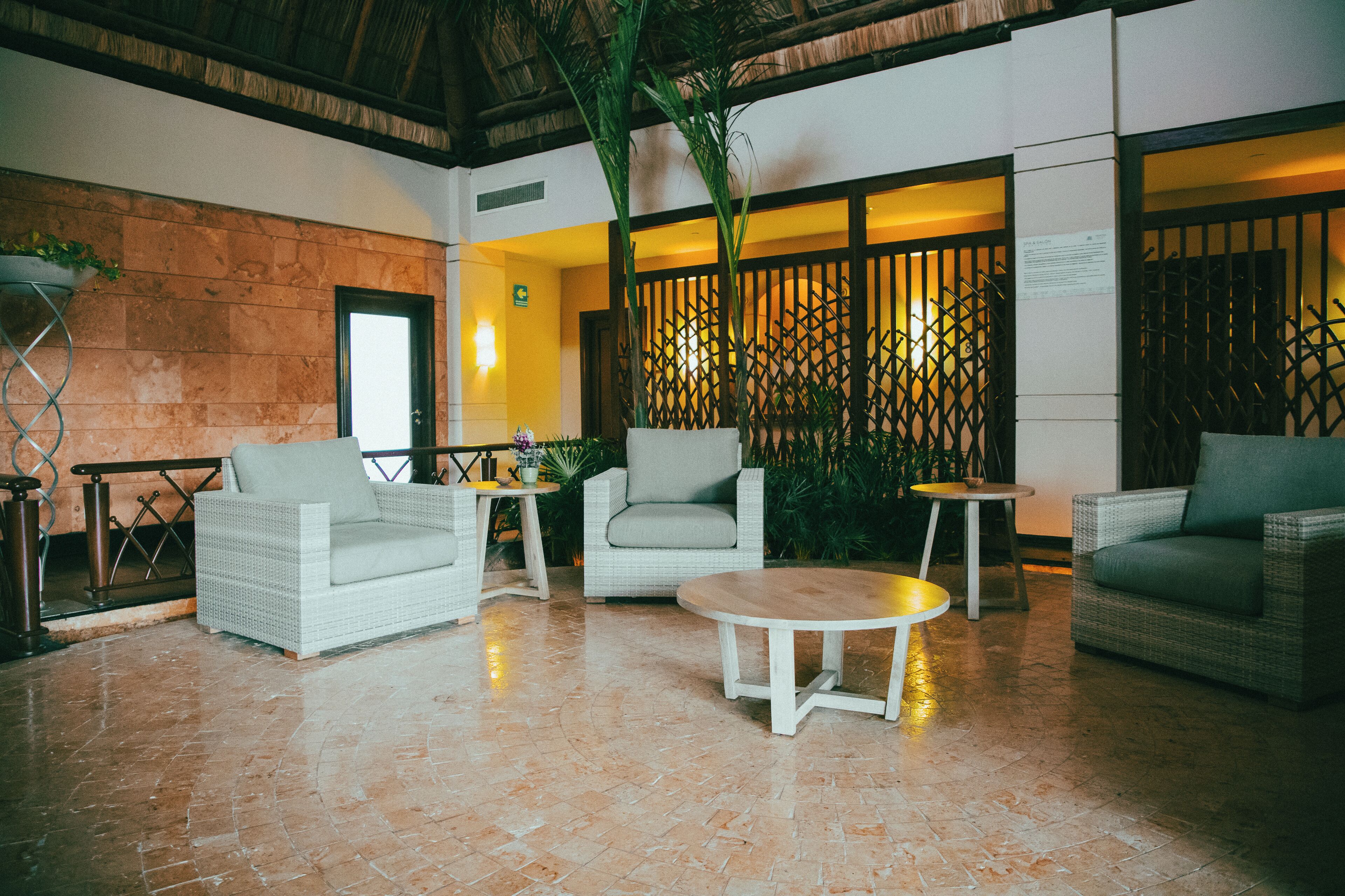 A spacious lobby with wicker furniture, a tiled floor, and a decorative plant.